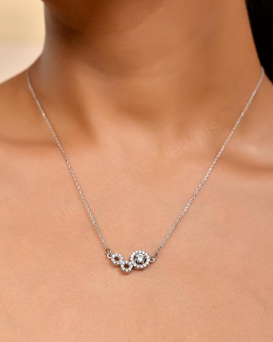 Silver necklace with a floral design on a person's neck against a neutral background