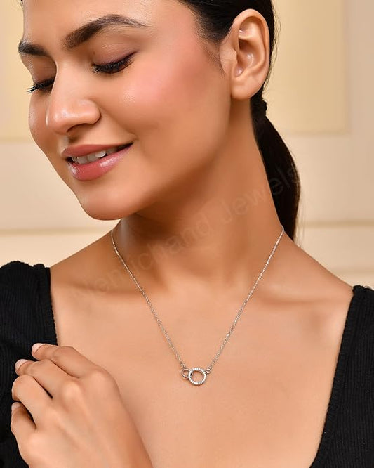 Woman wearing a silver necklace with a small circular pendant on a beige background